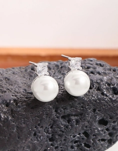 Details von eleganten Perlenohrringen mit Zirkonia-Stecker auf vulkanischem Gestein