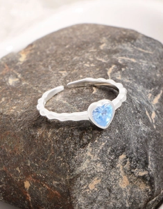 Detail of heart-shaped aquamarine gemstone ring with textured wave silver band
