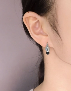 Macro view of S925 sterling silver earring featuring a black bead and sleek leaf design