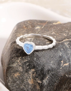 Macro shot of S925 silver ring featuring a light blue heart-shaped zircon on a textured rock