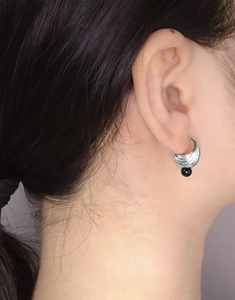 Close-up of a model wearing layered silver hoop earrings with black onyx bead drop