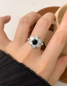 Close-up of S925 silver flower ring with black zircon center and white petals on hand