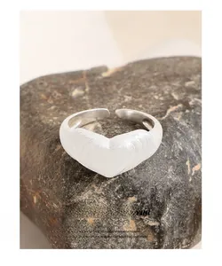 Vista dettagliata della trama opaca spazzolata e del design a cuore aperto dell'anello in argento