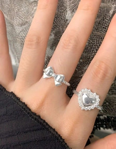 Gros plan de bagues en argent S925 avec cœur, nœud et zircons sur une main de femme