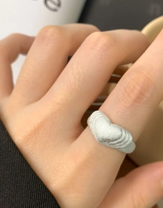 Macro dell'anello a cuore in argento sterling S925 spazzolato opaco sul dito modella