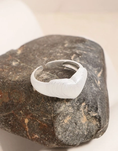 Dettaglio anello a cuore opaco su pietra con trama spazzolata e finitura argento