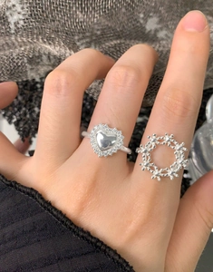Vue macro de bagues en argent avec cœur et anneau ajouré portées sur les doigts