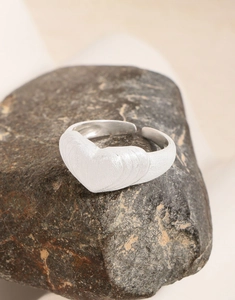 Dettaglio dell'anello opaco a forma di cuore su pietra naturale con trama spazzolata