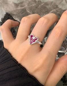 Close-up of S925 sterling silver ring featuring a heart-shaped red zircon inlay on finger
