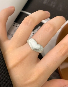 Dettaglio di un anello a cuore in argento spazzolato opaco al dito con texture elegante