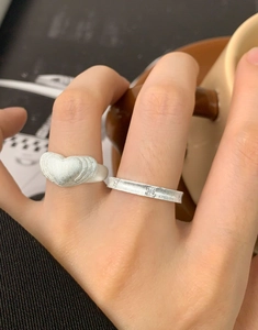 Dettaglio dell'anello a cuore opaco e fascia testurizzata con diamante sulla mano