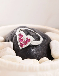 Macro detail of silver heart ring with pink zircon on black and white stones