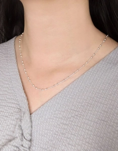 Primo piano di una collana a sfere in argento S925 minimalista sul collo di una donna