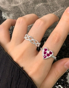 Detail of silver woven band ring and heart-shaped ring set with red zircons on hand