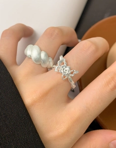 Detail of matte croissant ring and hollow rose bow ring on fingers in S925 sterling silver