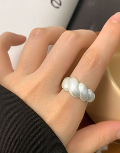 Macro detail of silver twisted croissant ring with a matte brushed finish on female finger