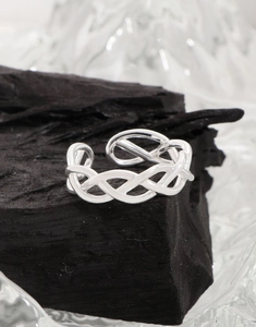 Macro shot of silver woven hollow ring featuring intricate Celtic textures on charcoal base