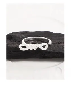 Detailed close-up of S925 sterling silver bow ring on a dark natural stone texture