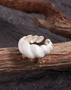 Macro shot of silver croissant ring with brushed matte texture on natural wood branch