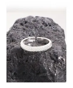 Macro shot of S925 sterling silver braided ring showcasing fine texture on volcanic stone