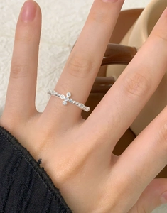 Close-up of S925 sterling silver cross ring with zircons on a beaded band worn on a hand