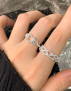 Detail of dual-finger silver woven ring with origami heart design on model hand