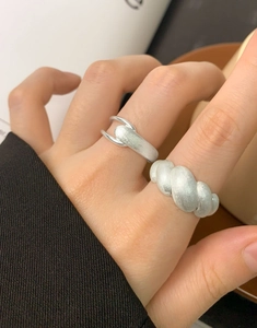 Close-up of matte silver croissant ring and interlocking band with brushed metal texture