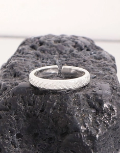 Close-up of S925 sterling silver twisted braided ring with adjustable open design on volcanic rock