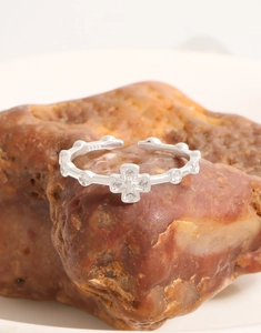 Macro shot of S925 sterling silver cross ring with pavé zircon on reddish raw stone