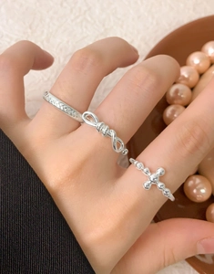 Detailed view of S925 sterling silver bow knot and cross bead ring set on model