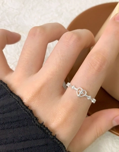 Detail of S925 sterling silver heart cross open ring worn on finger with soft lighting