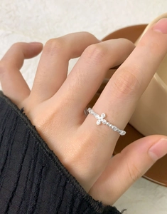 Detail of S925 sterling silver cross ring with zircons on beaded band worn on hand