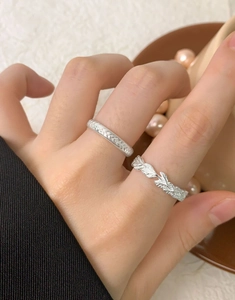 Detailed view of woven and leaf-shaped silver rings worn together on fingers