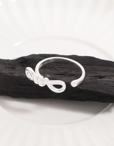 Detailed macro view of S925 sterling silver bowknot ring with hallmark on black charcoal