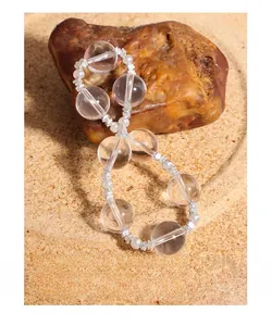 Detail of crystal beads and silver irregular spacers on textured sand background