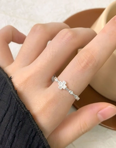 Macro detail of silver cross ring with zircons on finger over home cafe background