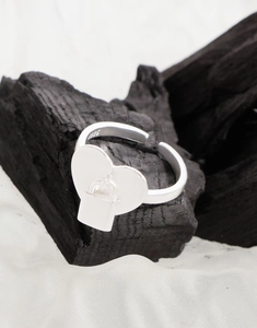 Detail eines Herzrings aus S925 Silber mit Mini-Schloss-Anhänger auf Holzkohlebasis