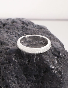 Macro detail of S925 sterling silver braided ring on black volcanic stone