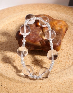 Macro shot of 925 sterling silver beads and natural clear crystal quartz on a stone base