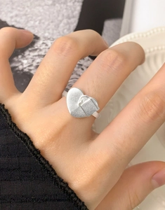 Nahaufnahme von mattem Herzschloss-Ring aus S925 Sterling Silber an Frauenhand