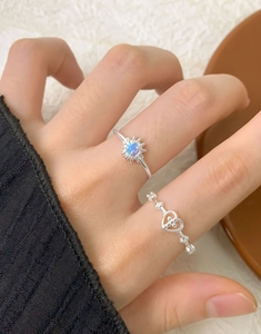 Detail of S925 silver sunflower opal ring and hollow heart ring set on a finger