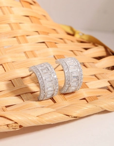 Macro detail of S925 silver C-shape earrings with baguette and round cubic zirconia
