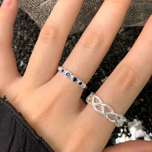 Cross-woven silver ring paired with a blue gemstone band showing intricate hollow design