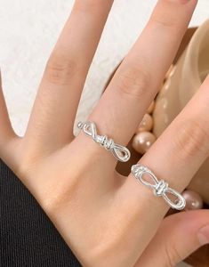 Macro detail of elegant S925 sterling silver bow knot rings worn on female fingers