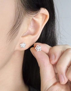 Close-up of S925 silver hollow flower earrings with white pearl inlay worn by a model