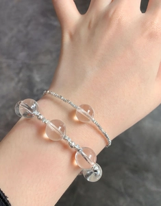 Close-up of stacked natural crystal bead bracelet and silver twist chain on wrist