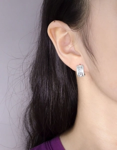 Close-up of sparkling silver hoop earrings with channel-set baguette and round zircons