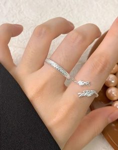 Macro detail of braided S925 silver ring and feather leaf ring on a finger