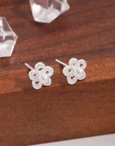 Macro detail of S925 silver hollow flower earrings with white shell pearls on wood