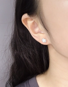Macro view of S925 silver flower earring with pearl on model's ear, showing detail